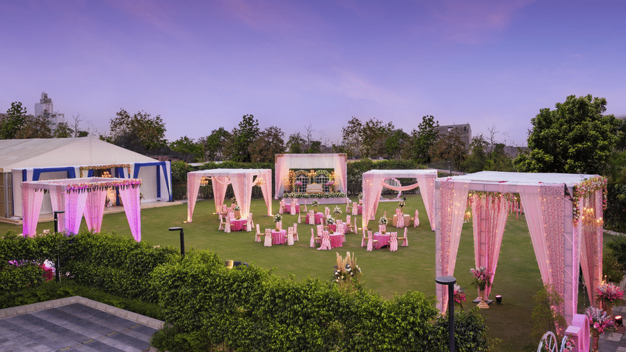 A group of canopies in an open space with clusters of tables and chairs scattered across the space - The Hideaway Banquets & Lawns, Greater Noida