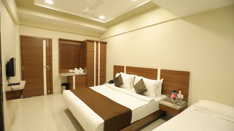 Extended view of the plush queen size bed in the Deluxe Room of the Highland Resort furnished with a wardrobe, wall-mounted TV, and bedside tables.