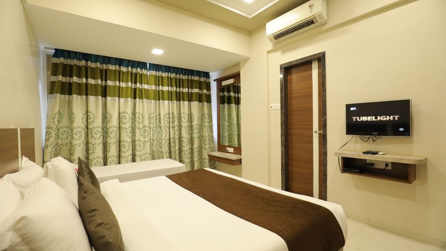 The queen size bed in the Deluxe Room of Highland Resort facing the wall-mounted TV.