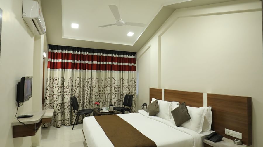 The Deluxe Room at Highland Resort features a queen size bed, a seating area for two, air-conditioning, and a wall-mounted TV.