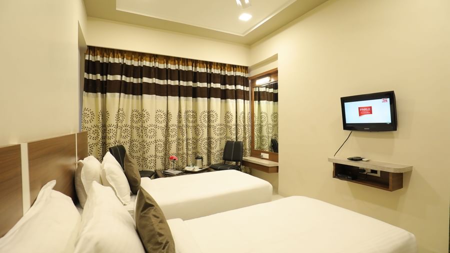 Corner view of twin beds in the Super Deluxe Rooms of Highland Resort, facing a wall-mounted TV.