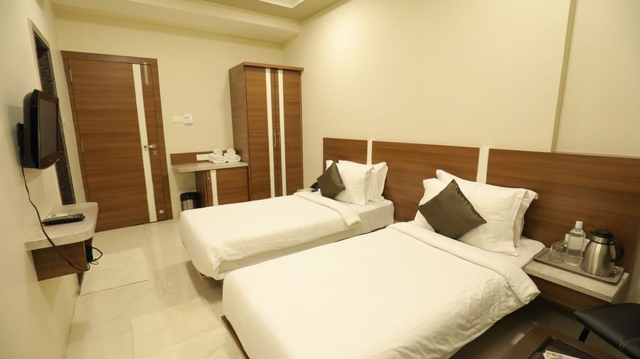 The Super Deluxe Rooms at Highland Resort feature twin beds facing a wall-mounted TV, a wardrobe, a bedside table on which a kettle is placed.