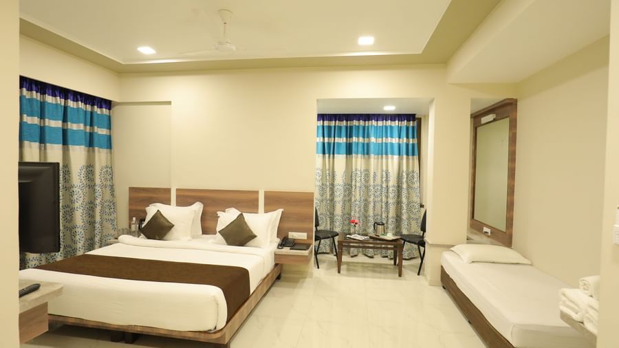 Front view of the Suite of Highland Resort featuring a king size bed, a single bed, a private seating area, and a wall-mounted TV.