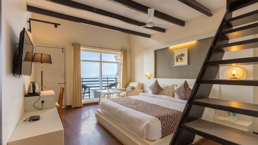 A modern guest suite featuring a white bed and a wooden staircase leading to a mezzanine level at Himalayas Resort By The Lake Hill, Mukteshwar.