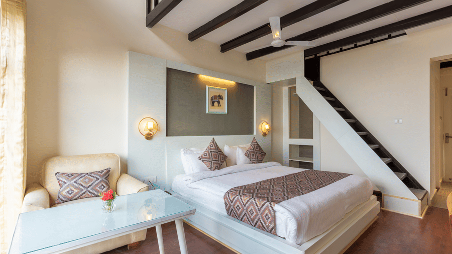 A high-angle view of a guest room with dark wooden ceiling beams and a staircase at Himalayas Resort By The Lake Hill, Mukteshwar.