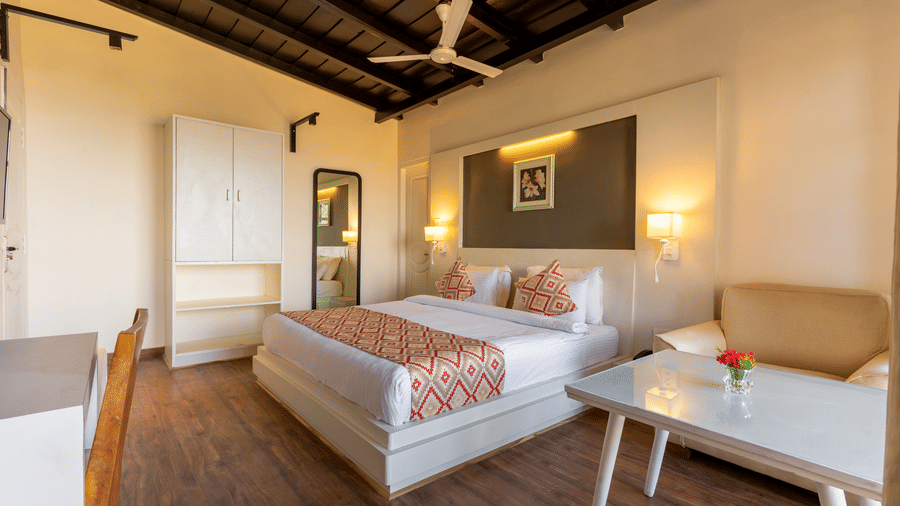 View of a bedroom showing a white wardrobe, a full-length mirror, and a bed with a patterned runner at Himalayas Resort By The Lake Hill, Mukteshwar.