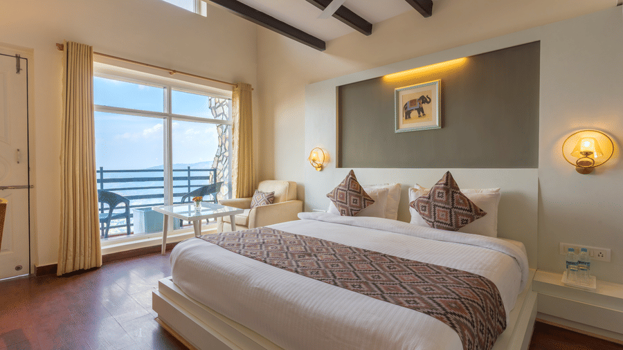 Guest room featuring a bed with a patterned runner and a large window overlooking the balcony at Himalayas Resort By The Lake Hill, Mukteshwar.