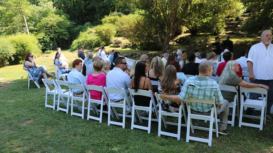 back view of the people gathered to witness a wedding under a tree shade - Historic Tapoco Lodge