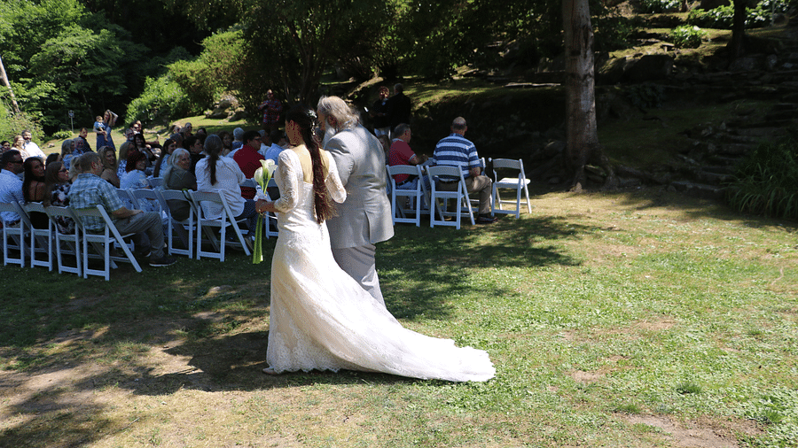 a bright image of a father walking along with the bride as they walk down the lawn - Historic Tapoco Lodge
