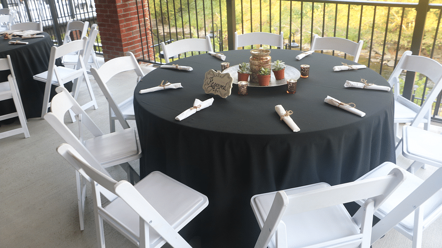 a round table with a dark grey colored table cloth spread over it with chairs surrounding it - Historic Tapoco Lodge