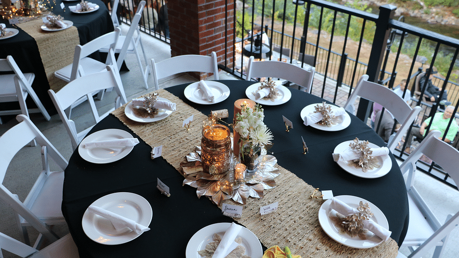 top view image of a beautifully set dining table with flowers and a big candle kept in the middle of the table surrounded by plates - Historic Tapoco Lodge