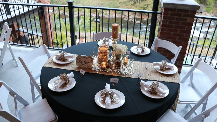 top view image of a dining table overlooking the flowing river with well set plates and utilities - Historic Tapoco Lodge