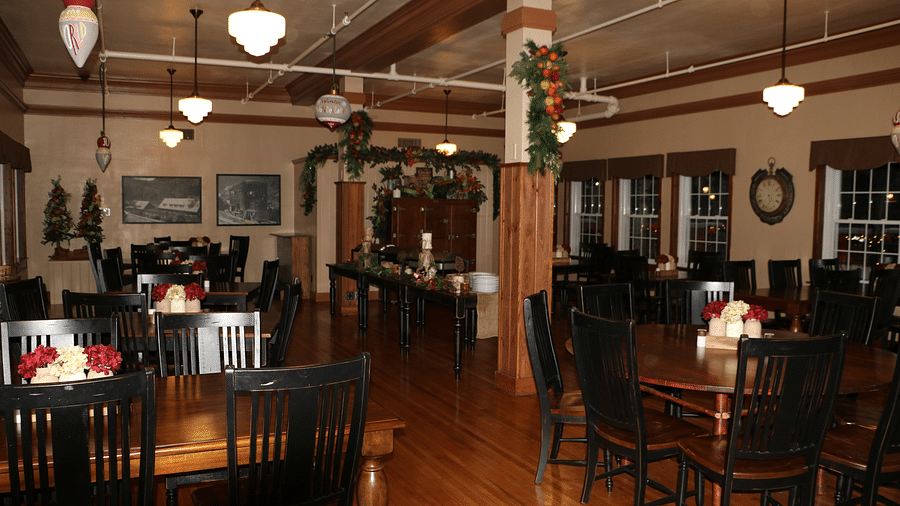 a cozy dining area with shiny wooden flooring featuring dining tables with small lamps illuminated over it - Historic Tapoco Lodge