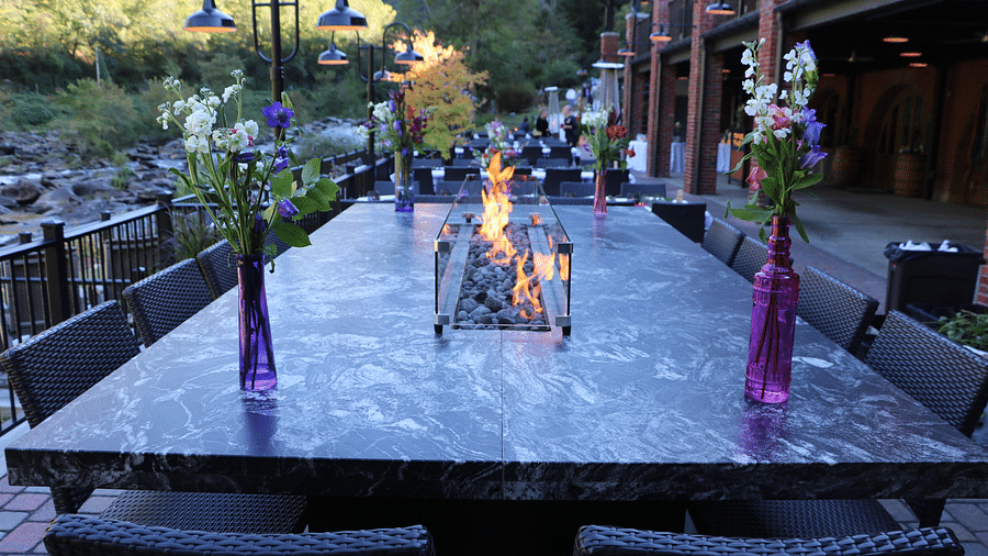 a dining table made of marble featuring a stone fire pit in the middle taken from a lower angle - Historic Tapoco Lodge