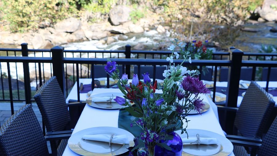 a close up view of a riverside dining table set with plates, cutlery, and a floral centerpiece - Historic Tapoco Lodge