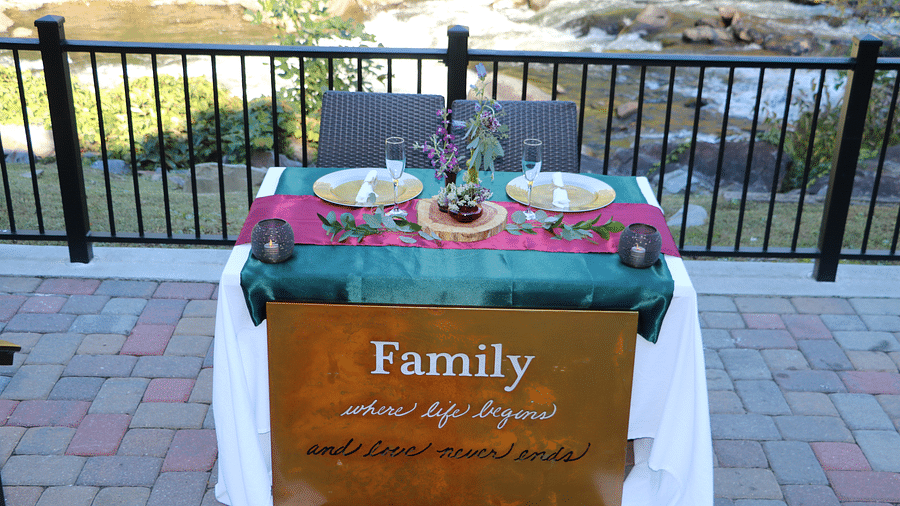 a table featuring a copper signage reading family with two plates set on the table and the beautiful river views in the background - Historic Tapoco Lodge