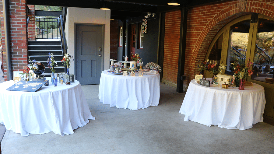 three round tables covered in huge white colored table clothes with flowers and various other goodies kept over it - Historic Tapoco Lodge