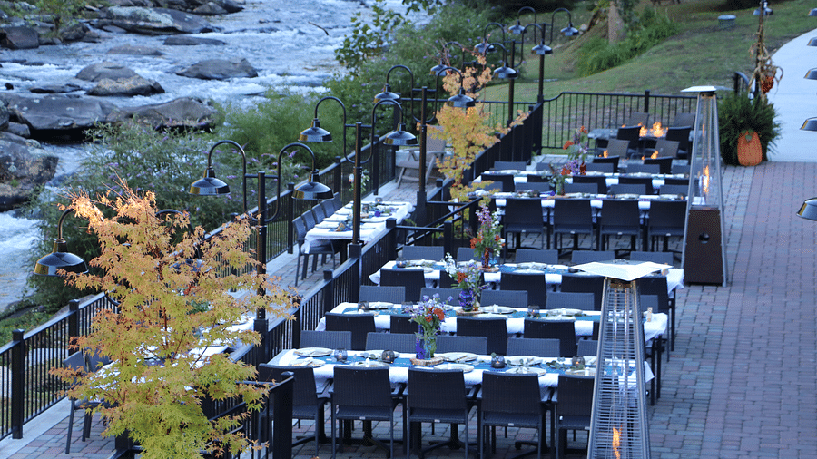 full view image of the outdoor dining area with various decorated tables along with tall gas lamps - Historic Tapoco Lodge