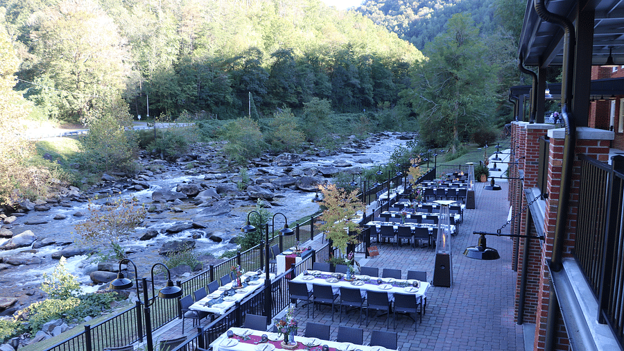 full view image of the outdoor dining area with lush green mountain views and the beautiful riverside views in the background - Historic Tapoco Lodge
