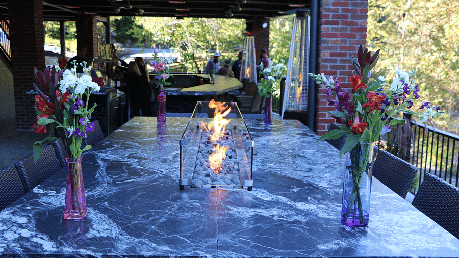 a dining table made of marble with two small flower vase kept with a small stone fire pit in the middle - Historic Tapoco Lodge