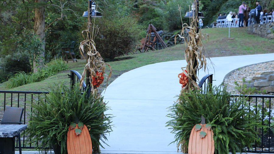a curved paved walkway decorated with autumn-themed pumpkins and greenery on either side - Historic Tapoco Lodge