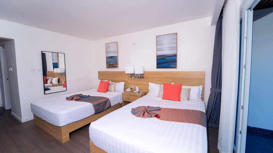 A Montego Bay hotel room with double beds, a wooden nightstand and an attached balcony at Hotel 39 Jamaica.