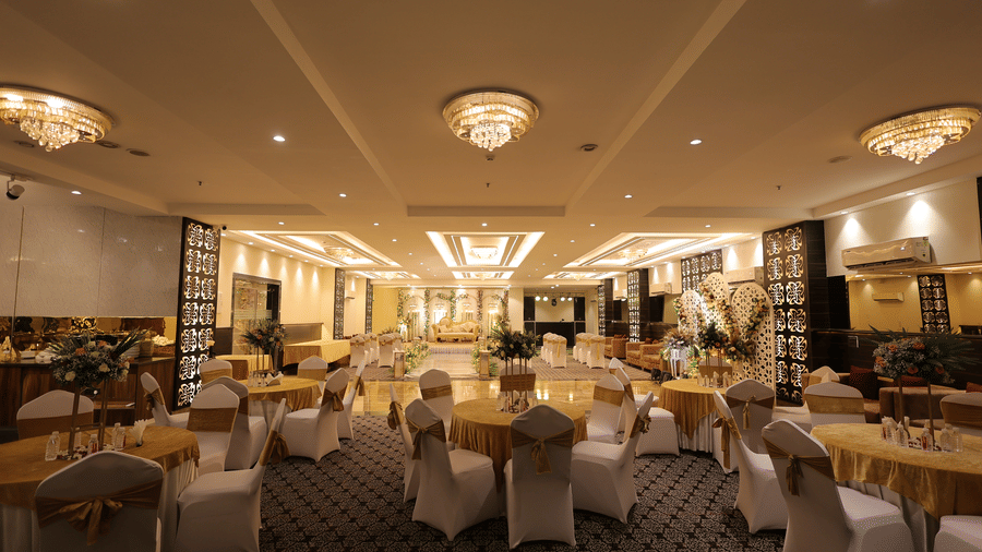 A formal banquet setup with round tables dressed in white linens and golden accents under elegant crystal chandeliers - Hotel 91 HUDA City Centre, Gurugram