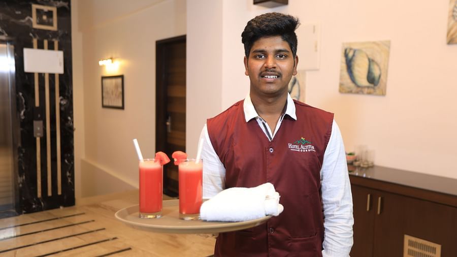 Image of a man holding a tray that has two glasses of drink on it at Hotel Altitude, Madikeri.