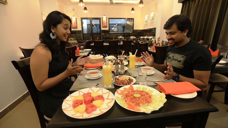 Image of two people with a variety of food placed before them at Hotel Altitude, Madikeri.