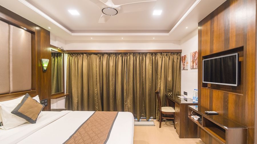 Side view of a room with a bed and a window on the side at Hotel Altitude, Madikeri.
