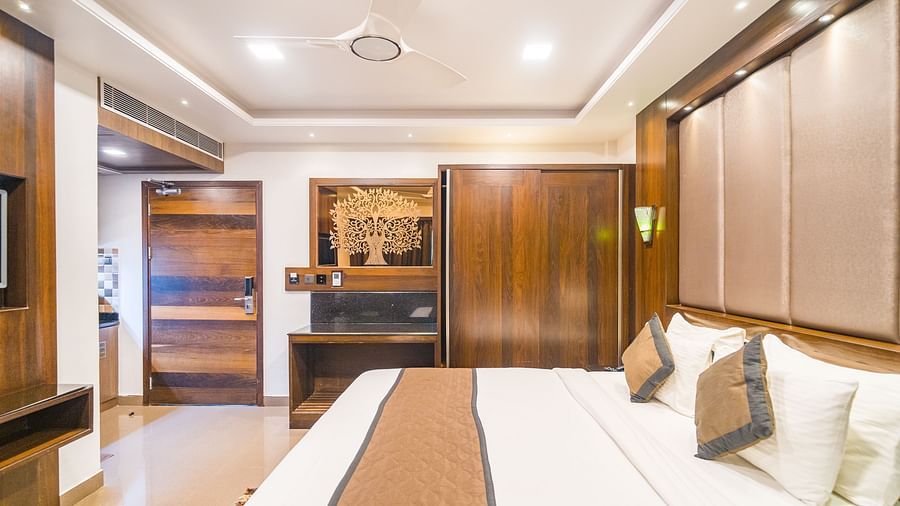 Side view of a room with a bed and a wooden wardrobe on the side at Hotel Altitude, Madikeri.
