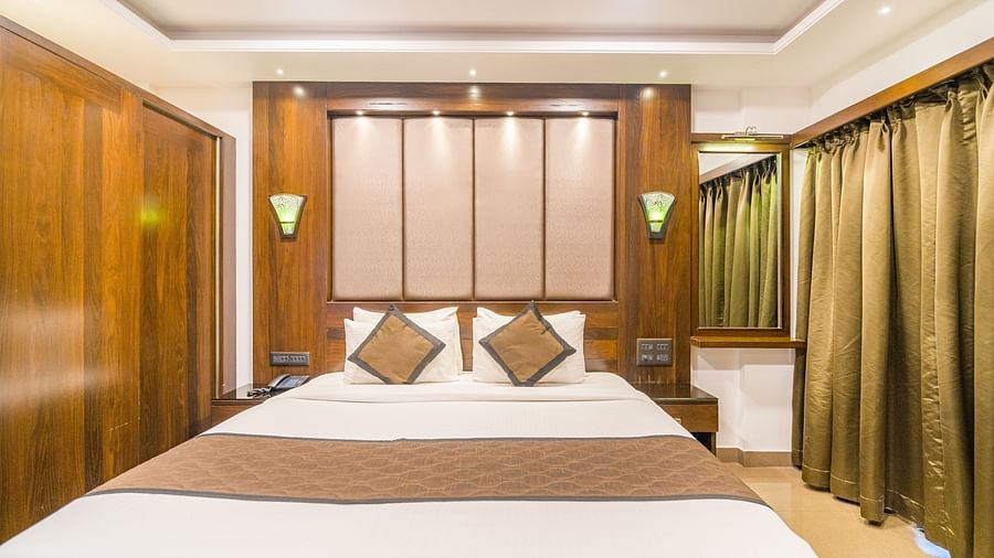 Front view of a room with a bed and a window on the side at Hotel Altitude, Madikeri.