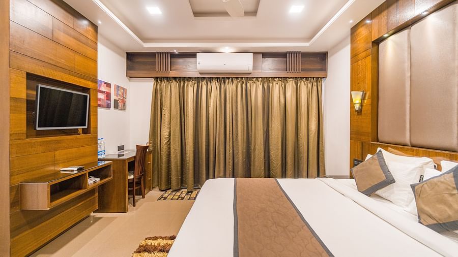 Side view of a room with a bed and a window on the side at Hotel Altitude, Madikeri.