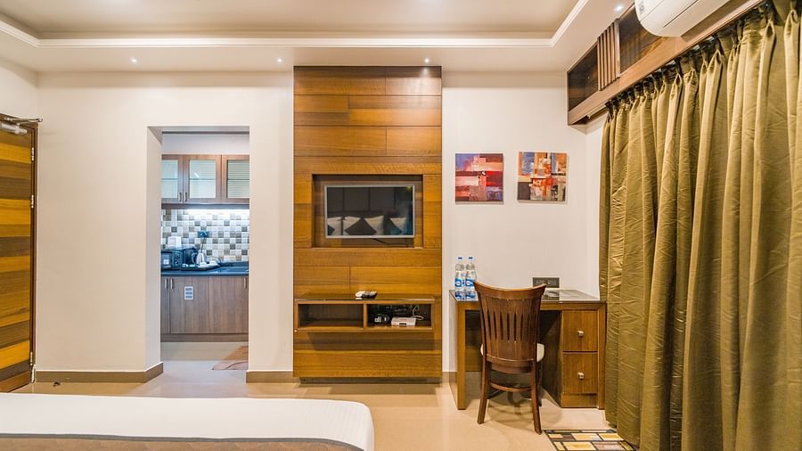 Image of a room with a bed and a table with a chair at Hotel Altitude, Madikeri.