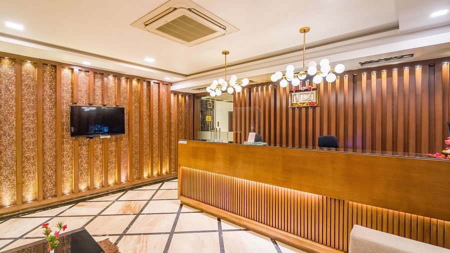 Image of a reception area with a wooden table and a television on the side at Hotel Altitude, Madikeri.