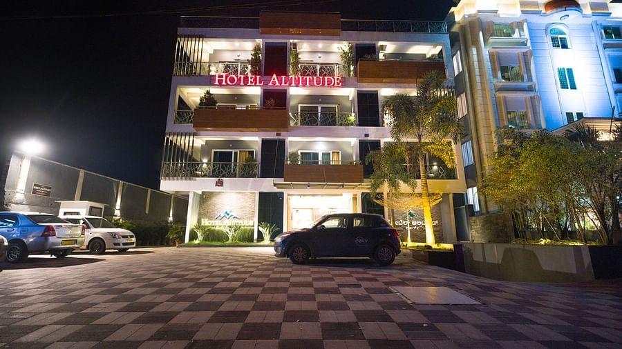 Night facade of Hotel Altitude, Madikeri with cars parked in front of it.