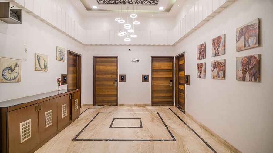 Image of a hall with four doors in the front and art prints on both sides of wall at Hotel Altitude, Madikeri.