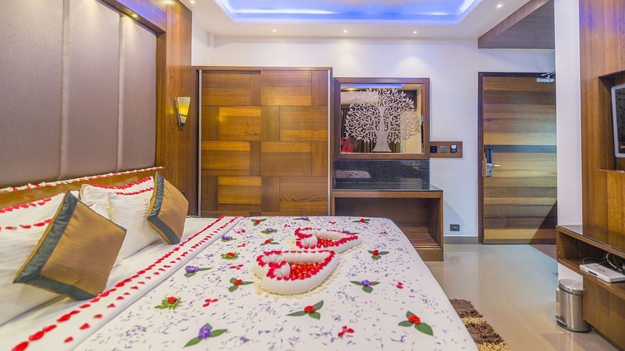 Side view of a room with a bed decorated with flower petals at Hotel Altitude, Madikeri.
