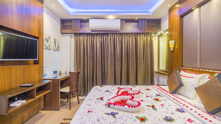 Side view of a room with a bed and a television in front at Hotel Altitude, Madikeri.