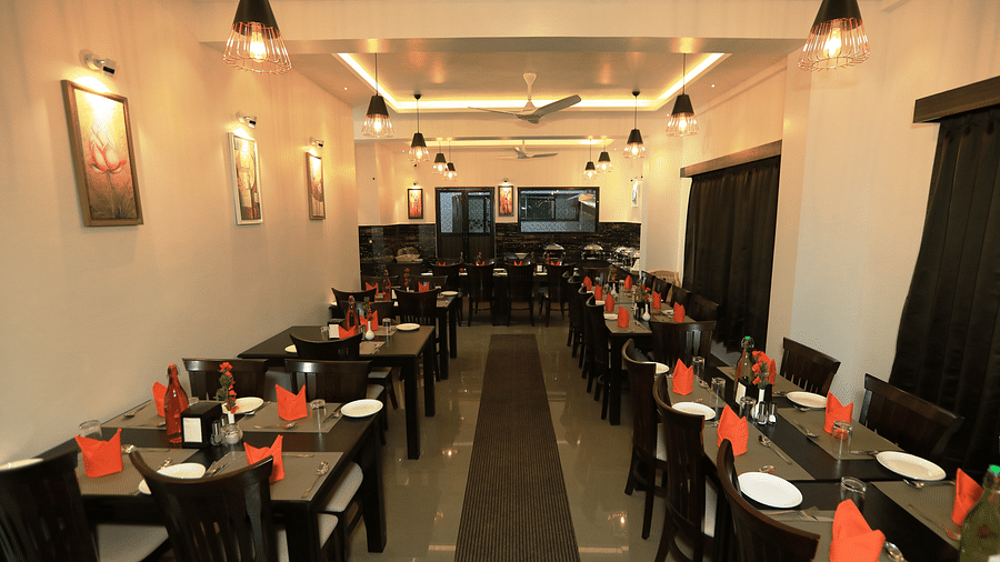 A dining space with tables and chairs and lights on the ceiling at Hotel Altitude, Madikeri.