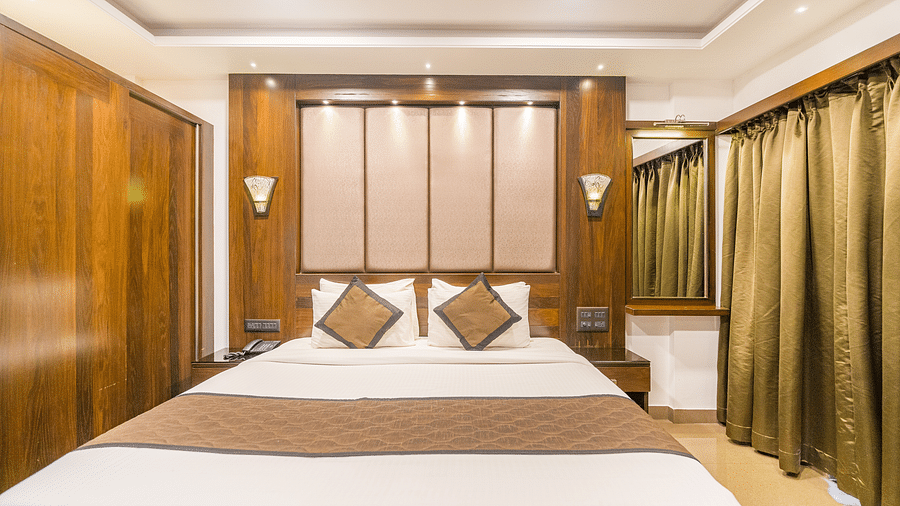 Front view of a room with a bed and a window on the side at Hotel Altitude, Madikeri.