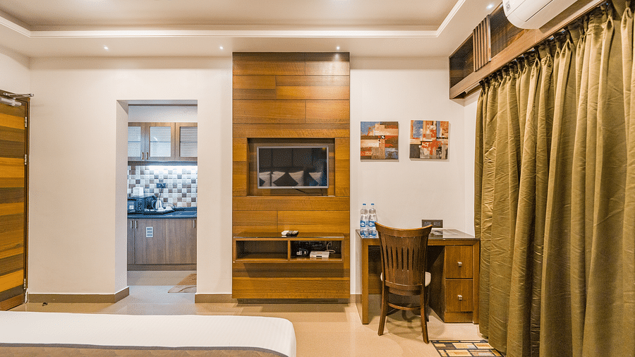 A room with a bed and a table with a chair at Hotel Altitude, Madikeri.