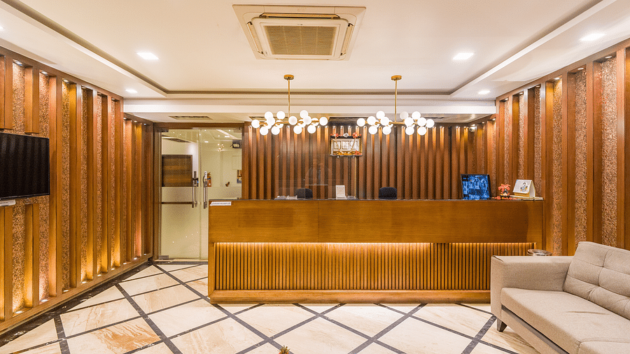 A reception area with a sofa on the side and a television in front of it at Hotel Altitude, Madikeri.