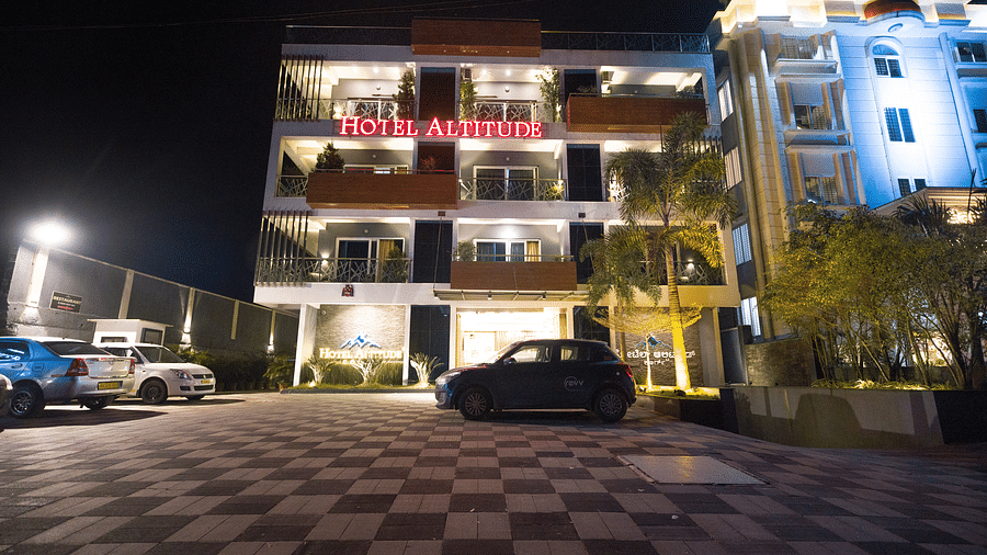 Night facade of Hotel Altitude, Madikeri with cars parked in front of it.