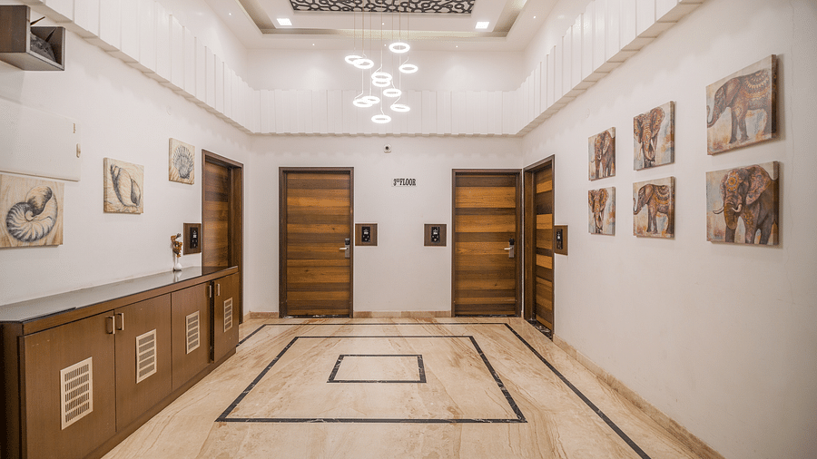 A hall with four doors in the front and art prints on both sides of wall at Hotel Altitude, Madikeri.