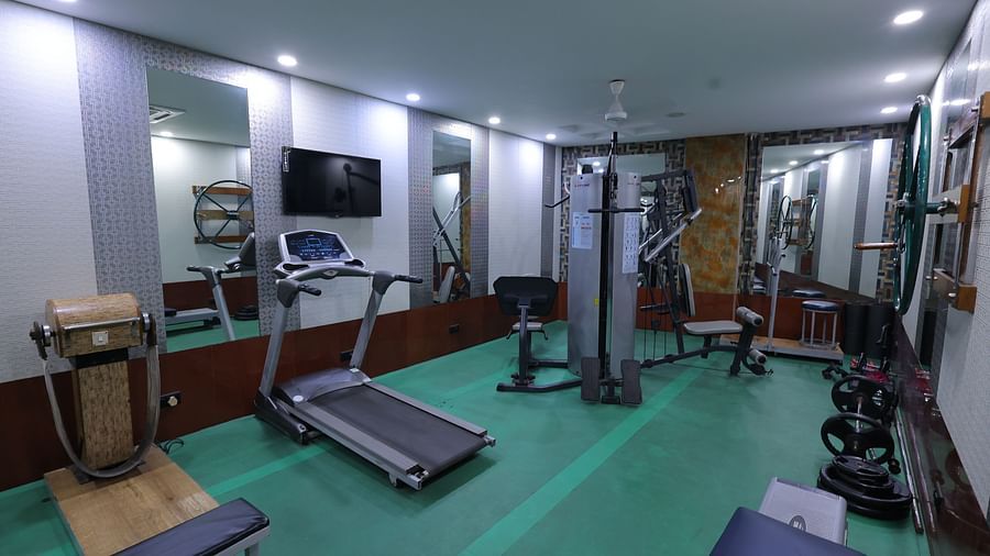 Overview image of a gym at Hotel Amar with gym equipment and a mirror 