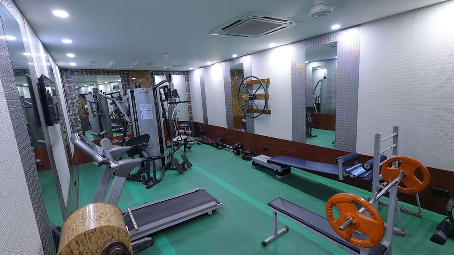 Side view image of a gym at Hotel Amar with gym equipment and a mirror 