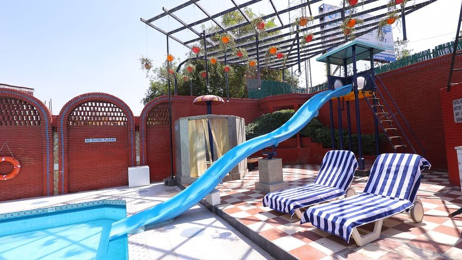 Image of a swimming  pool  of Hotel Amar with a slide and  lounge chairs 