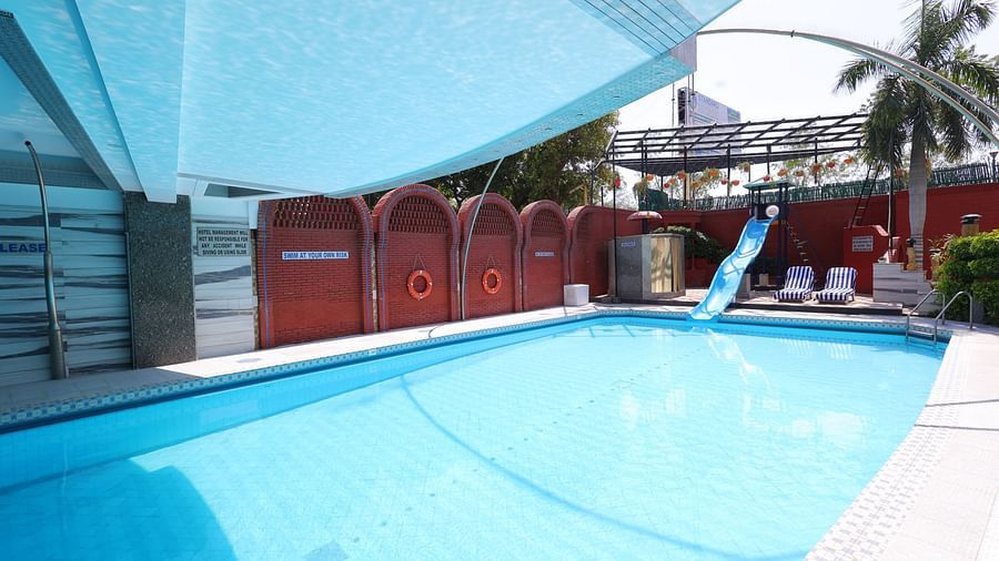 Image of a swimming  pool  of Hotel Amar with a slide and surrounded by plants 