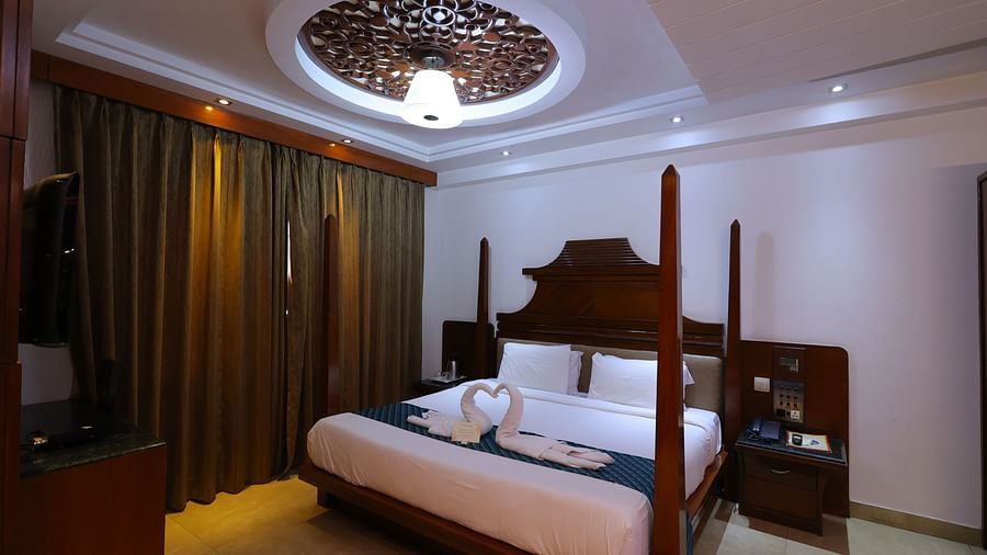 Image of Premium room at Hotel Amar with a bed, table and towels shaped as swans kept on bed.